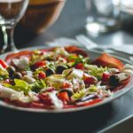 Enticing Mediterranean salad featuring olives, cheese, and fresh vegetables on a ceramic plate.
